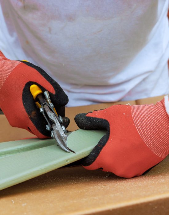 Worker cuts plastic vinyl siding to size with a of scissors before installing it Worker cuts plastic vinyl siding to size with a of scissors before installing it